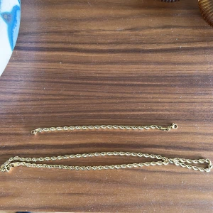 Guldpläterat halsband och armband - Säljer ett snyggt set med tvinnat halsband och matchande armband i guldpläterad metall. Båda har en klassisk karbinhake och den tvinnade designen ger en cool och trendig look. Perfekt för dig som gillar stilrena accessoarer med lite extra bling. Rostfritt stål!
