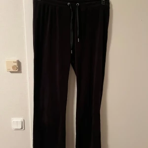Svarta mjukisbyxor med snörning - Svarta mjukisbyxor med raka ben och snörning i midjan. Byxorna är gjorda i ett mjukt och skönt material som passar perfekt för chill dagar hemma eller när du vill vara extra bekväm. Klassisk och enkel design utan synliga loggor.Katt finns i hemmet 