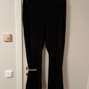 Svarta sammetsbyxor från Gina Tricot - Mörka svarta byxor i mjuk sammet från Gina Tricot. Byxorna har elastisk midja och raka ben med en lätt utsvängd bootcut-look. Perfekta för dig som gillar en chill men ändå snygg stil. Superbekväma och passar till många outfits. Snöret är borta Katt finns i hemmet 