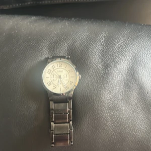 Silverfärgad klocka från o.n.e - Stilren klocka från o.n.e med rund urtavla i silver och tydliga siffror. Klockan har en metall-länk i silverfärg och flera små urtavlor för extra funktioner. Perfekt accessoar för dig som gillar klassisk design.