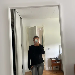 Svart glittrig tröja Scotch & Soda XS - Supersnygg svart tröja från Scotch & Soda i storlek XS. Tröjan har glittrigt tyg och coola volangdetaljer vid axlarna. Långärmad och med en normal passform, perfekt för dig som vill sticka ut lite extra.