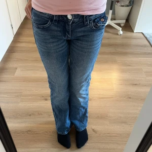 Blå bootcut jeans med broderad ficka - Low waisted boot cut jeans från Gina Young i storlek 158. De sitter bra i benen och man kan även spänna åt i midjan. 