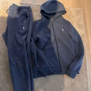 Mörkblå mjukisbyxor Polo Ralph Lauren - Mörkblå mjukisbyxor från Polo Ralph Lauren med klassisk broderad logga på benet. Byxorna har dragsko i midjan och är tillverkade i mjuk bomullsblandning för maximal komfort. Perfekta för chill dagar eller när du vill vara extra bekväm.