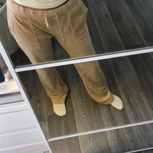 Beiga mjukisbyxor Juicy Couture M - Säljer ett par beiga mjukisbyxor från Juicy Couture i storlek M. Byxorna har dragsko i midjan, stora fickor fram och en bakficka med knapp. Mjukt material och relaxed passform, perfekta för chill dagar. Jag har sytt in dem så passar nån som har storlek s-xs jag är 160cm lång och dem är lite långa som man ser på bilden