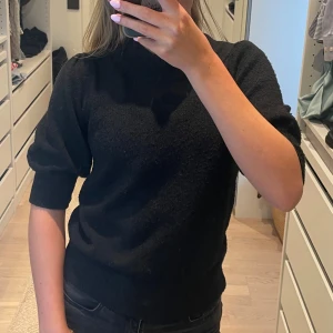 Svart stickad tröja från JDY - Svart stickad tröja från JDY med puffiga halvlånga ärmar. Tröjan har en klassisk, enkel design och är perfekt för lager-på-lager. Mjuk och skön känsla, passar till allt.