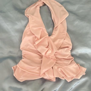 Ljusrosa omlott halterneck topp - Supersöt ljusrosa halterneck topp med omlott och volangdetaljer. Öppen i ryggen aldrig använd då den inte passar min stil  