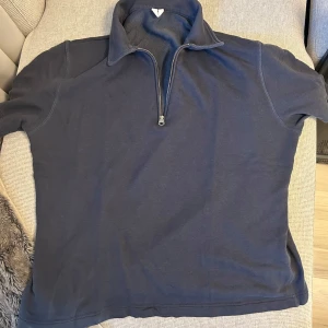 Mörkblå half zip tröja - En stilren mörkblå tröja med half zip och krage. Tröjan har korta ärmar.
