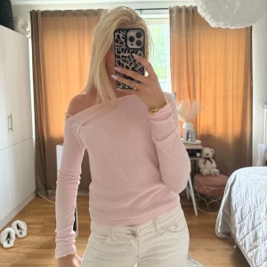 Ljusrosa offshoulder stickad tröja - Supersöt ljusrosa stickad tröja med offshoulder och lång ärm. Perfekt för dig som gillar en feminin och trendig stil. Tröjan är ribbad och sitter snyggt på kroppen, passar både till jeans och kjol.