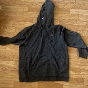 Mörkgrå hoodie från JJXX XL - Mörkgrå hoodie från JJXX i storlek XL. Klassisk modell med huva och snörning, samt en stor magficka framtill. Liten vit JJXX-logga på bröstet. Perfekt för chill dagar och enkel att matcha med jeans eller mjukisbyxor.