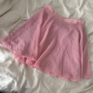 Rosa kortkjol från NA-KD - Säljer en rosa kortkjol från NA-KD. Kjolen har ett tunt, lätt tyg med ett extra lager under för att inte bli genomskinlig. Passar perfekt till ett festligare tillfälle. Använt en gång.