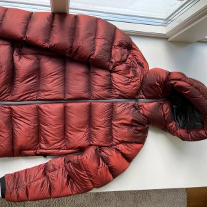 Röd dunjacka från Sail Racing XS - Säljer en fet röd dunjacka från Sail Racing i storlek XS. Jackan är pösig och har huva, dragkedja och svarta detaljer. Materialet är dun och polyester, perfekt för kalla dagar. Snygg metallicröd färg som sticker ut och håller dig varm hela vintern.