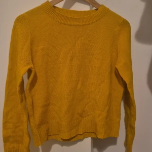 Gul stickad tröja med rund hals - Snygg gul stickad tröja med rund halsringning och ribbade muddar. Perfekt för dig som vill ha en färgklick i garderoben. Långärmad och mjuk, passar till jeans eller kjol. Har haft den länge men inte haft på mig den många gånger
