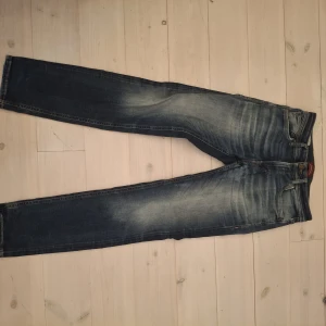 Blå jeans i slim fit, stl 28/32 - Snygga blå jeans med slitningar och tvättade detaljer. Klassisk femficksmodell med raka ben och normal passform. Jeansen har gylf med knapp och dragkedja samt kontrastsömmar. Perfekta till en avslappnad streetstil.