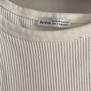 Vit ribbad långklänning Bershka - Supersnygg vit ribbad långklänning från Bershka. Klänningen är ärmlös med smala axelband och har en tight passform men materialet är stretchigt 