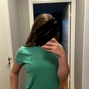 Grön t-shirt från Polo Ralph Lauren - Snygg grön t-shirt från Polo Ralph Lauren med klassisk passform och ikoniska lilla loggan broderad på bröstet. T-shirten är i mjuk bomull och har korta ärmar och rund hals. Perfekt till jeans eller shorts för en clean och enkel look. Är som ny! Den sitter mer som en XS/S, den sitter inte som en M. Jag själv har storlek S 