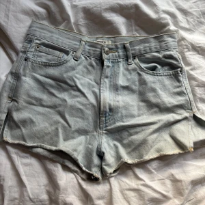 Ljusblå jeansshorts från Forever 21 - Snygga ljusblå jeansshorts från Forever 21 med slit på sidorna . De har hög midja och en avslappnad passform, perfekta för varma dagar. Shortsen har bälteshällor och knappgylf för en klassisk denimlook.