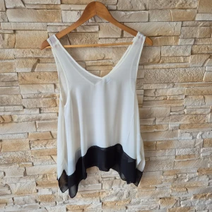 Vit och svart linnetopp från Gina Tricot - Säljer en snygg vit linnetopp från Gina Tricot med svart kant nertill. Toppen har v-ringning och är ärmlös, perfekt för varma dagar. Luftig och lätt i materialet, passar till många olika stilar. Genomskinlig. Aldrig använd