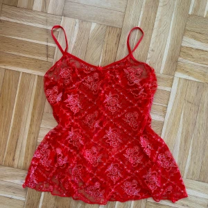 Rött glittrigt spets linne - Säljer detta röda spets/mesh-linne med glittriga blommor, väldigt stretchigt. Köpt second hand och saknar lapp men skulle säga att storleken motsvarar s.❤️🌟