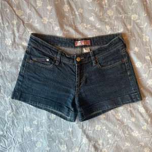 Mörkblå low-waist jeansshorts - Säljer ett par mörkblå jeansshorts från &NOW med klassisk femficksdesign. Shortsen har låg midja och stängs med knapp och dragkedja. Perfekta för varma dagar! Midjemåttet tvärsöver är 34,5 cm 😊