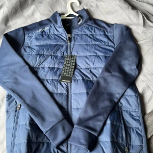 Blå quiltad jacka från Druids - Säljer en blå quiltad jacka från Druids med dragkedja. Jackan har långa ärmar och två sidofickor med dragkedja. Perfekt för kyliga dagar och snygg till vardags. Märket syns på bröstet och etiketten sitter kvar.