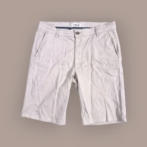 Beige shorts från Solid - Snygga beige shorts från Solid med normal passform och klassisk design. De har fickor på sidorna, bälteshällor och stängs med knapp och dragkedja. Perfekta för varma dagar och enkel att matcha med olika outfits.