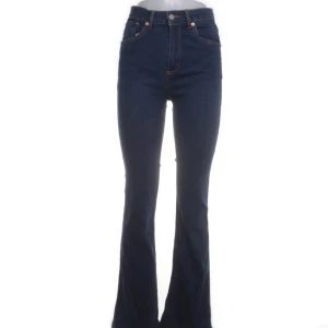 Mörkblå bootcut jeans - Mörkblå jeans med hög midja och bootcut passform. Klassisk femficksmodell med dragkedja och knapp framtill. Perfekta för dig som gillar en tidlös och snygg stil.