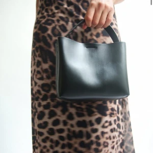 Svart handväska i skinn - Säljer en stilren svart handväska från NAKD, nypris 400kr. Använd fåtal gånger🖤Väskan har en praktisk dragkedja på insidan för extra säkerhet. Perfekt för dig som gillar minimalistisk och tidlös stil.