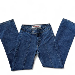 Jeans - Snygga blå jeansbyxor med raka ben och markerade vita sömmar längs framsidan. Ca 67 cm runt midjan och 69 i innerbenslängd.