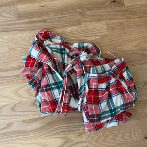 Flanell pyjamas set - Mysiga pyjamasbyxor i röd, grön och vit rutig bomull med resår i midjan och snörning. Perfekta för hemmakvällar eller när du vill vara extra bekväm. Matchande överdel finns också. Flanell tyg säljer då de är för små