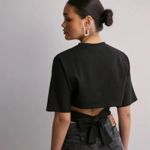 Svart topp från Nelly  - Säljer svart topp från Nelly som har knytning i ryggen. 