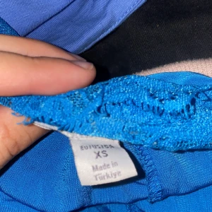 Blå klänning med spetsdetaljer - Säljer ett blått linne från newyorker i storlek XS. linnet har smala axelband, v-ringning och fina spetsdetaljer upptill. Perfekt för varma dagar och har en luftig känsla.