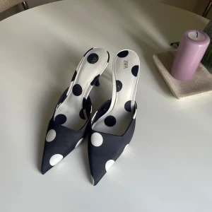 Svarta pumps med vita prickar från Zara - Säljer ett par svarta klackar från Zara med stora vita prickar på som jag var för snabb på att riva bort prislappen. Storlek 40 men passar mig som har 39. Postar från Frankrike. Nypris 450. Mitt pris 350. Dom är oanvända.