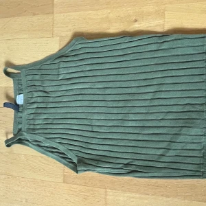 Olivgrön ribbad linnetopp från Divided - Säljer en olivgrön ribbad linnetopp från Divided. Toppen är ärmlös med smala axelband och har en snygg ribbad struktur som ger en trendig look. Perfekt att matcha med jeans eller kjol för en avslappnad stil.