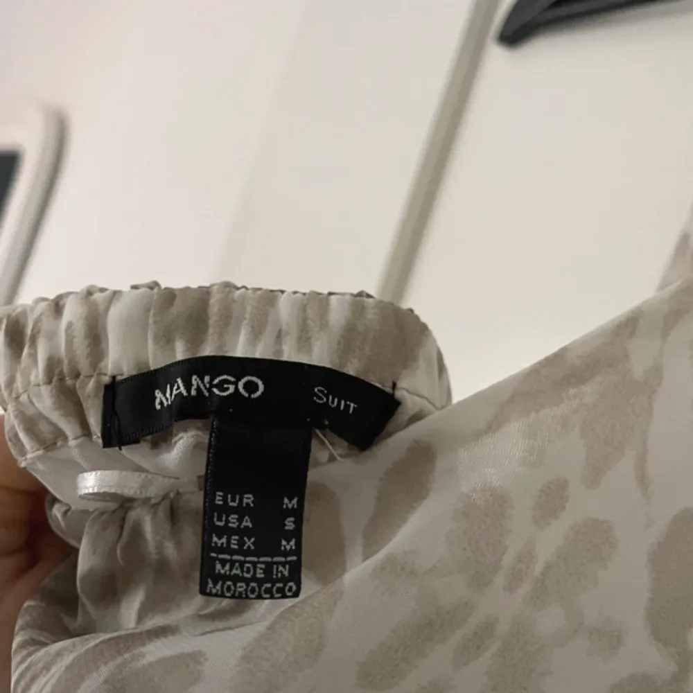 Säljer en snygg beige klänning från Mango med leopardmönster. Klänningen har en luftig passform och är ärmlös med knytning i halsen. Perfekt för en stilren look! Öppen i ryggen . Mekot.