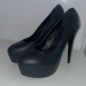 Svarta pumps från NLY - Snygga svarta pumps från NLY med hög klack och platåsula. Tillverkade i syntetmaterial med en elegant och stilren design. Perfekta för att höja din stil till nästa nivå. Inga större defekter mer en någon skråma som knappt syns.