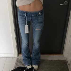 Blå bootcut jeans med slitningar - Snygga blå bootcut jeans med slitningar på knäna. De har en låg midja, säljer pga kommer ej till användning. Använda 2 gånger så de är i bra skick. Storleken är xs men skulle sägas att de är rätt så stretch bara i materialet