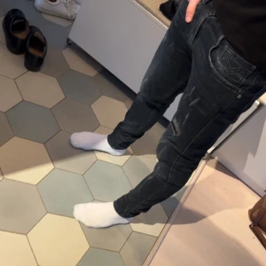 Svarta jeans från Replay - Snygga svarta jeans från Replay med en cool, sliten look. De har en klassisk femficksdesign och är perfekta för en avslappnad stil. Märket Replay är känt för sin kvalitet och stil. 
