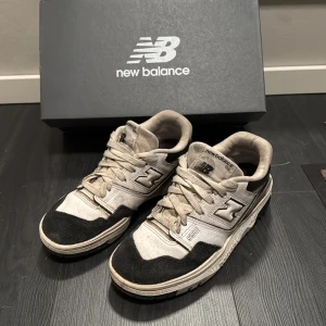 New Balance 550 sneakers - Säljer ett par New Balance 550 sneakers i svart och vit. Skorna har en klassisk design med snörning och New Balance-loggan på sidan. Perfekta för en stilren look.