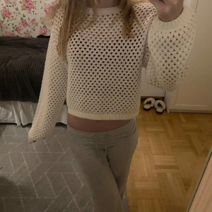 Vit stickad tröja - Säljer en vit stickad tröja med ett luftigt hålmönster. Tröjan har långa ärmar och en rund halsringning. Perfekt för lager-på-lager-stil eller som en lättare tröja för svalare dagar.