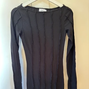 Svart ribbad långärmad klänning från NA-KD (Hanna Schönberg) storlek S - Snygg svart ribbad klänning med långa ärmar och en stilren design. Perfekt för en chic och minimalistisk look. 