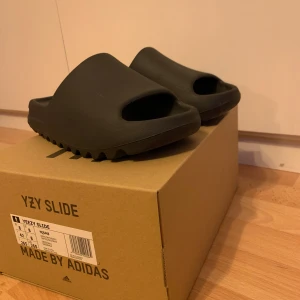 Svarta Yeezy Slide - färg onyx  - Säljer ett par svarta Yeezy Slide från. Dessa slides har en minimalistisk design med en bekväm passform och är perfekta för avslappnade tillfällen. Ny pris 1799 - 2199kr