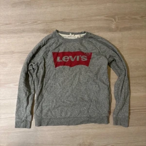 Grå sweatshirt från Levi's - Säljer en grå sweatshirt från Levi's med deras ikoniska röda logga på bröstet. Tröjan har långa ärmar och en rund halsringning. Perfekt för en avslappnad stil. 🩶