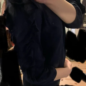 Mörkblå topp med volangdetaljer  - Säljer en mörkblå topp från Lindex med volangdetaljer längs ärmarna. Toppen har en rund halsringning 💙