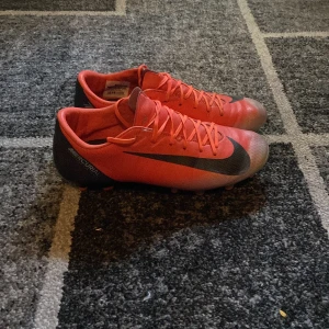 Röda fotbollsskor från Nike - Säljer nu mina Nike mercurial cr7 edition, eftersom dom har blivit för små! Skorna är perfekt för dig som vill sticka ut på planen och spela med style för en billig peng!