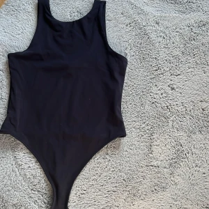 Svart body  - Snygg och stilren svart bodymed rundad halsringning. Enkel design som ger en klassisk look.