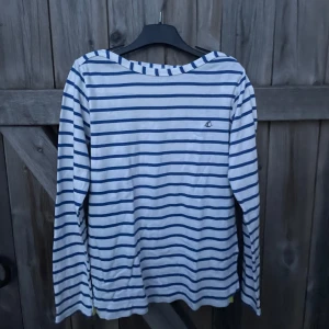 Randig långärmad tröja Petit Bateau - Snygg långärmad tröja från Petit Bateau i klassiskt marinblått och vitt randigt mönster. Tröjan har en avslappnad passform och är tillverkad i mjuk bomull, perfekt för en chill och stilren look. 