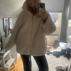 Hm teddy jacka - Supermysig och oversized teddyjacka i beige/vit med dragkedja framtill. Jackan har två stora fickor och är perfekt för kalla dagar. Den fluffiga looken ger en chill vibe och passar perfekt till jeans eller leggings. Den är i storlek xl men tycker den sitter snyggt oversize på mig som har s, hör av dig vid frågor💗