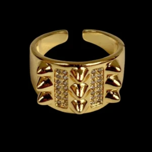 Guldig ring med nitar och stenar - Cool guldig ring med öppningsbar baksida, dekorerad med små nitar och två rader glittrande stenar framtill. Ringen har en chunky design som sticker ut och passar perfekt för dig som gillar edgy accessoarer.