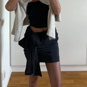 Svart kort kjol med en rosett - Säljer en svart kort kjol med stor rosett i sidan. 