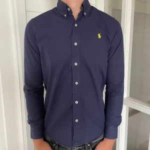 Polo Ralph lauren skjorta  - Säljer denna riktigt snygga mörkblåa Ralph lauren skjorta, den är i mycket bra skick men har en pytteliten fläck som knappt syns (kontakta för närmare bild) annars mycket bra skick, storlek S modell slim fit jag på bilden är 183 cm för längdreferens, den är 73 cm lång och 50 cm bred , hör gärna av dig vid frågor!